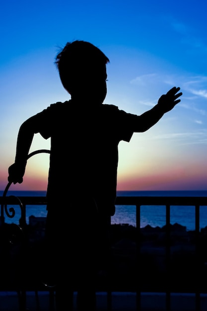 Счастливый ребенок во время силуэта морского фона