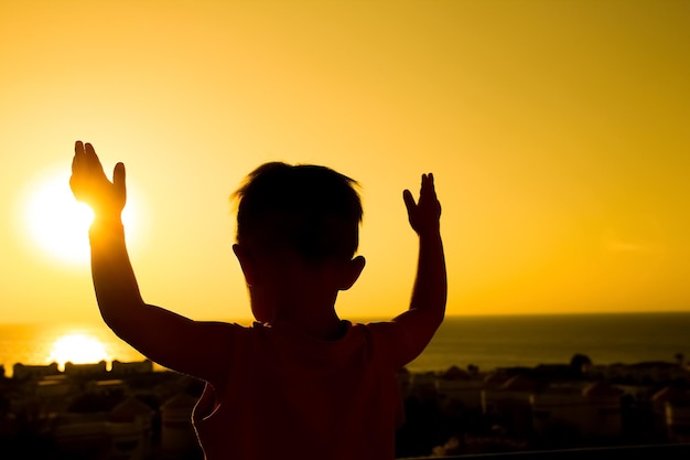 Happy child at the time of the silhouette of the sea background