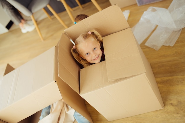 Happy child. Top view of a pretty cute girl while sitting in the box