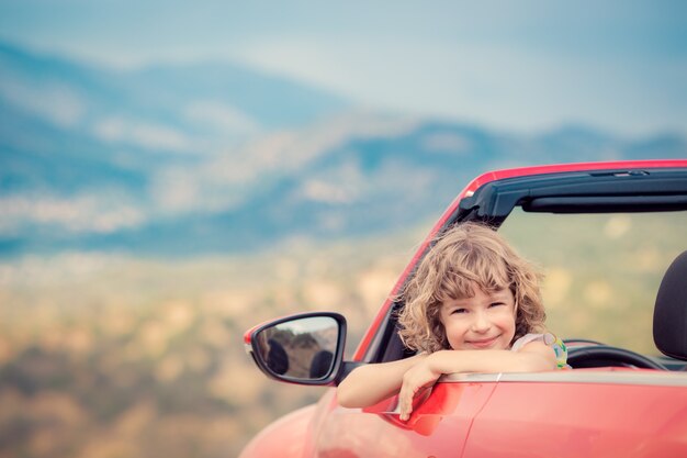 山で車で幸せな子供旅行赤いカブリオレで楽しんでいる子供夏休みのコンセプト