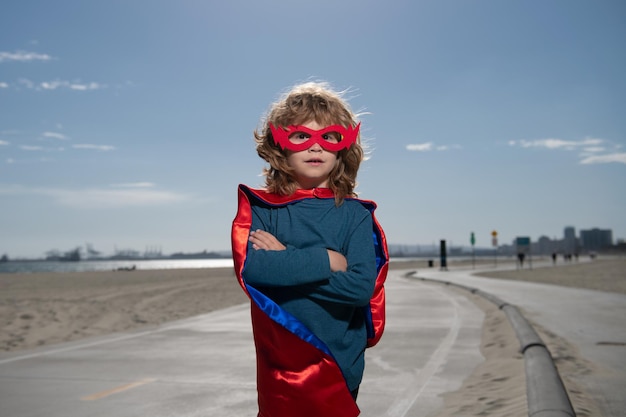 푸른 여름 하늘 배경 아이 하비에 대 한 슈퍼 히어로 의상 슈퍼 영웅 아이를 입고 행복 한 아이
