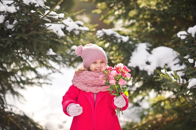 Happy child in the winter forest with a bouquet of flowers 931