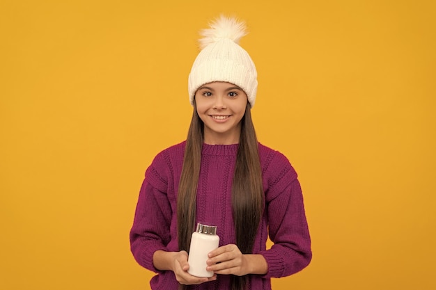 Bambino felice in cappello invernale con la salute del vasetto della pillola