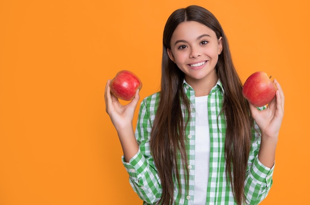 Happy child with apple fruit on yellow background