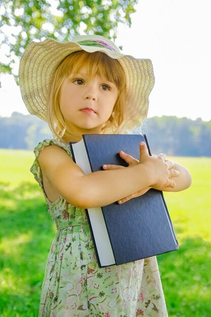 A happy child with a book on the nature of the Bible in the Park