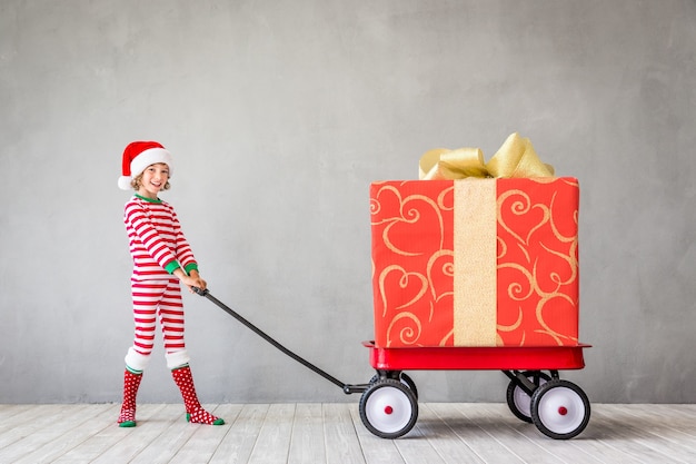 Happy child with Christmas gift. Kid having fun at home