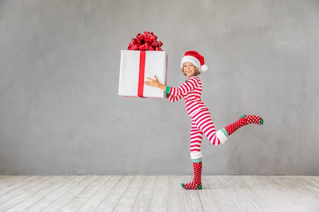 Happy child with Christmas gift. Kid having fun at home