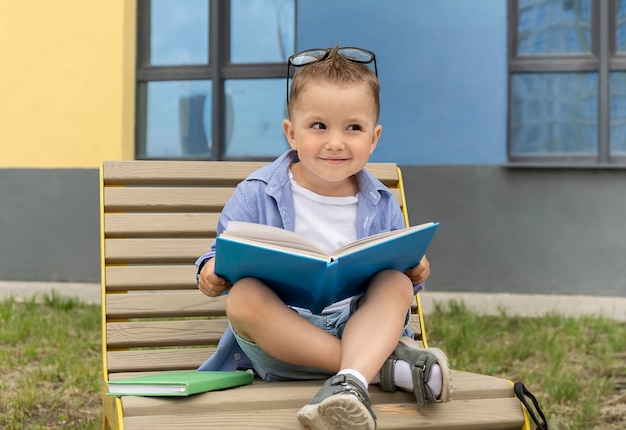 A happy child with glasses holds an open book in his hands