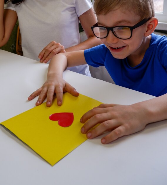 Foto un bambino felice con gli occhiali ha realizzato un biglietto con le sue stesse mani per la festa del papà di san valentino