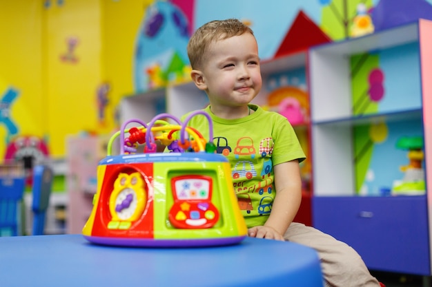 Foto il bambino felice con un giocattolo interessante in età prescolare e all'asilo sta giocando con un giocattolo colorato