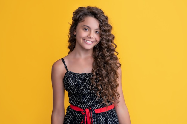 Happy child with long brunette afro hair on yellow background