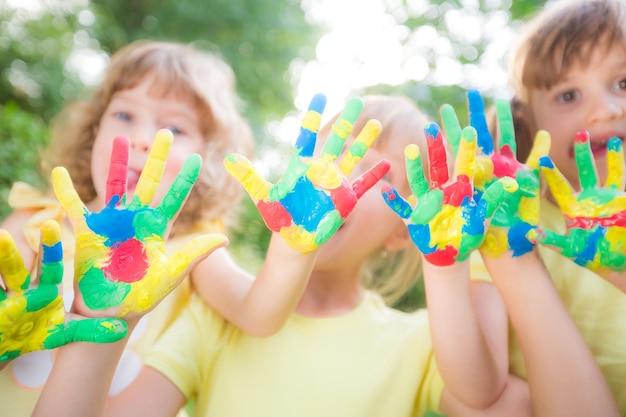 Happy child with painted hands against green spring background