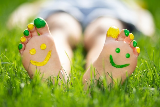야외 발에 미소를 가진 행복한 아이 녹색 봄 잔디에 누워있는 아이 생태학과 건강한 라이프 스타일 개념