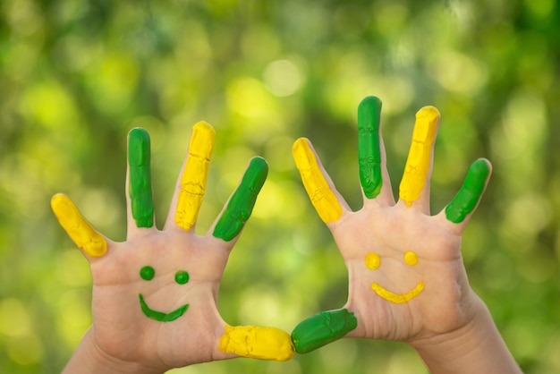 Happy child with smile on hands against green spring background. Ecology concept