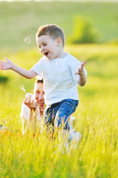 happy child and woman outdoor playing with soap bubble on meadow