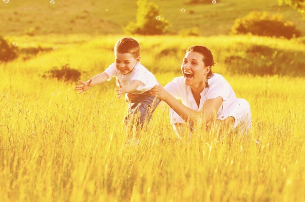 happy child and woman outdoor playing with soap bubble on meadow