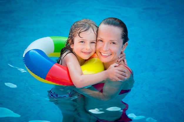 Happy child and woman playing in swimming pool