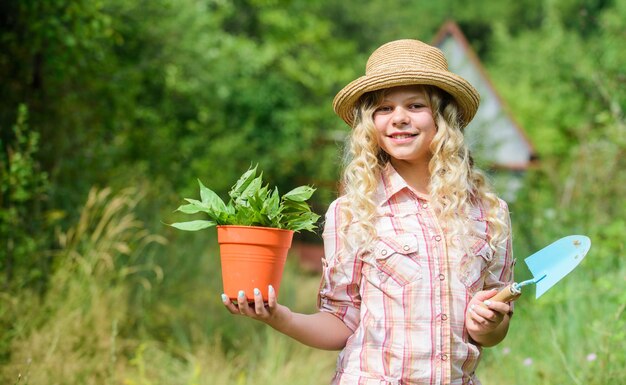 Happy childhood Child in hat with shoulder blade small shovel hoe Happy smiling gardener girl Ranch girl Planting plants Little kid hold flower pot Spring country works Happy childrens day