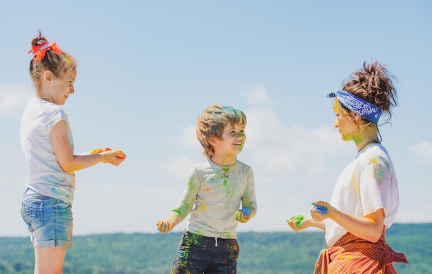 Bambini felici dell'infanzia che giocano con i colori holi festival dei colori bambini con la faccia imbrattata di luminoso