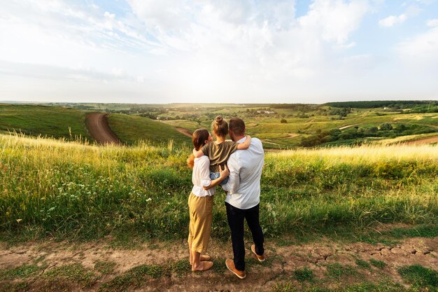 Happy Childhood. Rear view portrait of family of three standing in the middle of the field and enjoying landscape