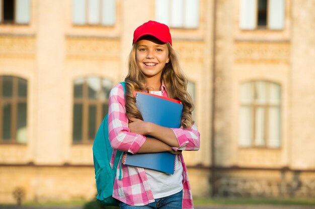 Happy childhood teen girl with book pretty child little girl going to read study literature for children learn with document folder knowledge day modern school education