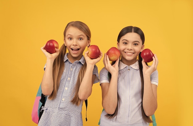 Happy children back to school holding apples for healthy eating yellow background childhood nutrition