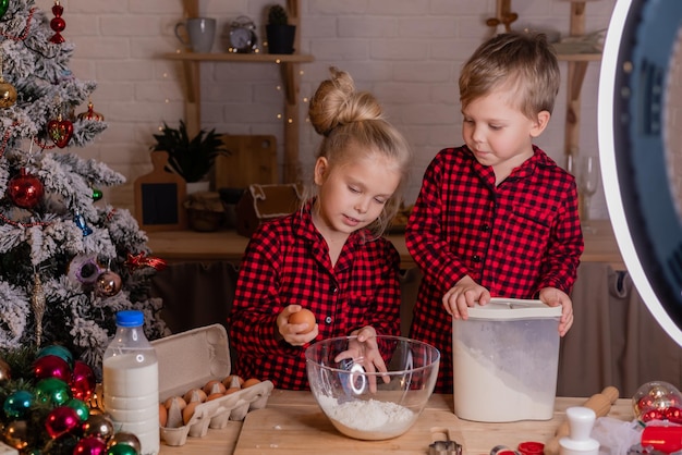 Happy children bake Christmas cookies at home in the kitchen