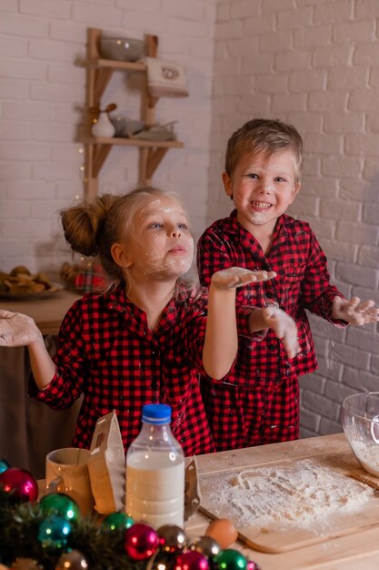 Happy children bake Christmas cookies at home in the kitchen