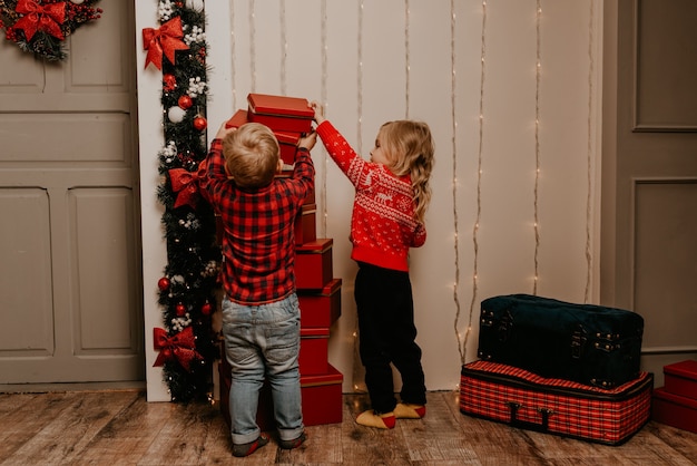 Happy children celebrating New Year and Christmas at decorated Christmas tree and garlands