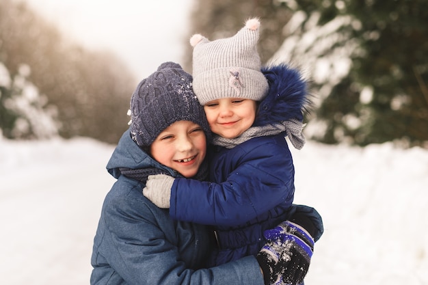 Happy children cuddle in winter in the woods. Brother and sister together