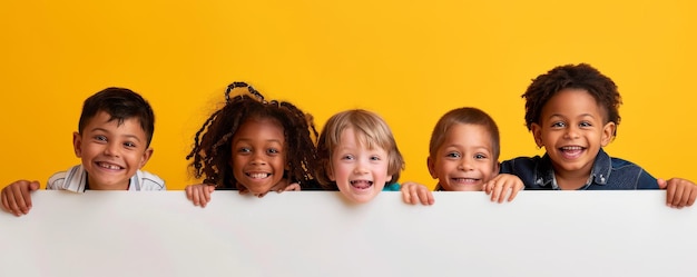 異なる人種の幸せな子供たちが黄色い背景のホワイトボードを見つめている