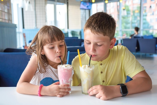 Happy children drink milkshakes in a cafe Closeup | Premium Photo