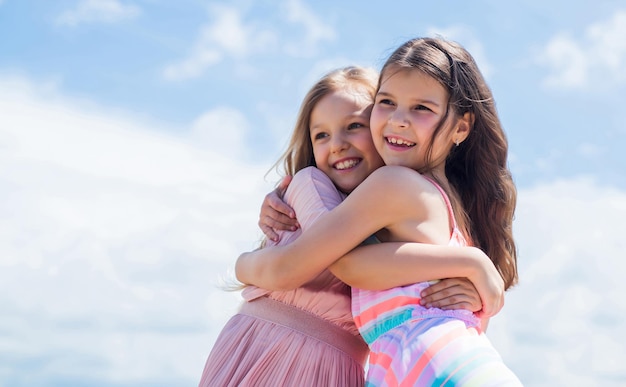 Happy children embrace on sky background, family love.