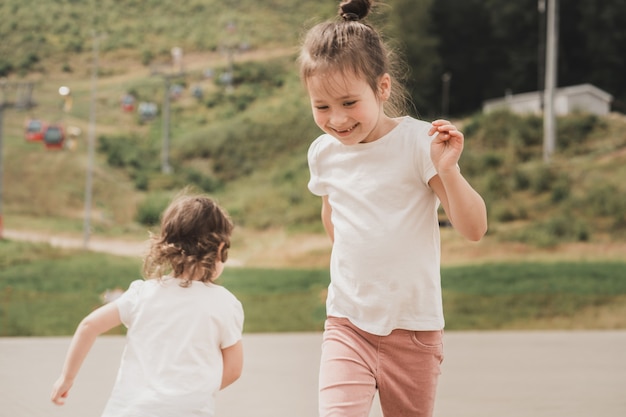 幸せな子供たちは人生を楽しんで、白いTシャツを着た子供たちが走り、お互いに楽しく遊んでいます...