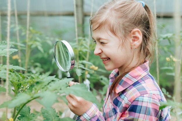 Happy children girl with loupe studying learning nature outside child education concept little curio...