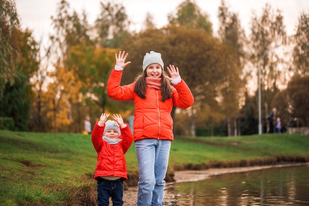 Happy children girls with paper boat in a puddle in autumn on nature outdoors