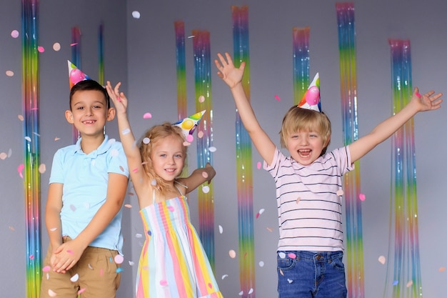 Happy children have fun during the holidays and jump in colorful confetti