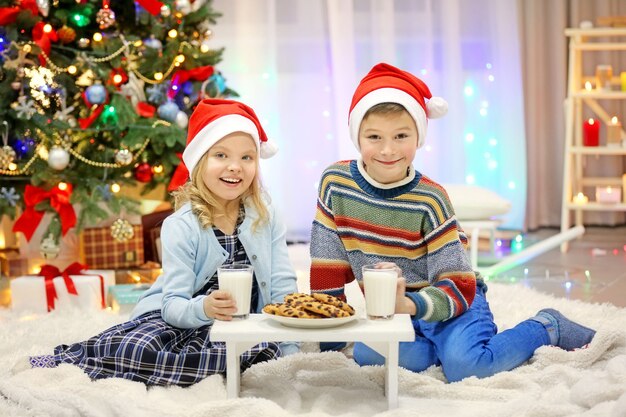 I bambini felici mangiano nella stanza di natale addobbata