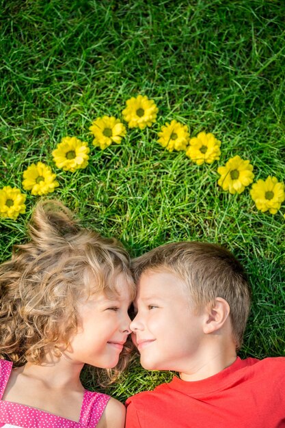 Happy children having fun outdoors House shape spring flowers Boy and girl lying on green grass Sweet home Renovation and moving concept