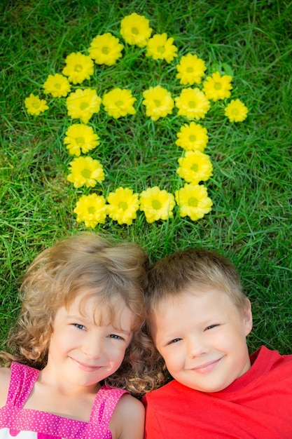 Happy children having fun outdoors House shape spring flowers Boy and girl lying on green grass Sweet home Renovation and moving concept