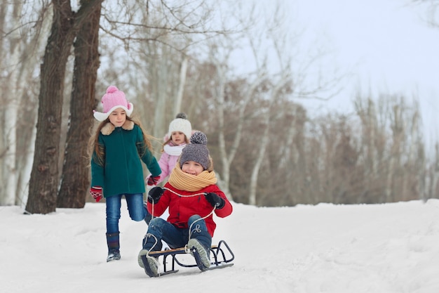 Счастливые дети веселятся и катаются на санках по снегу