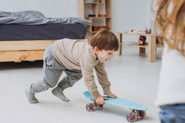 Happy children having fun with skateboards on floor in room at home.