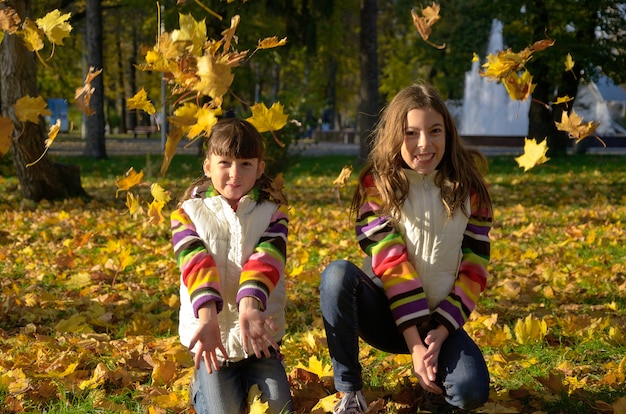 Фото Счастливые дети в осеннем парке, активные дети веселятся и играют с желтыми листьями на улице