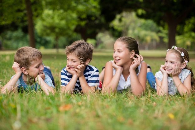 Happy children interacting with each other while lying on grass