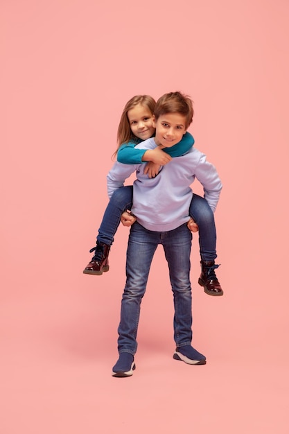 Happy children isolated on coral pink studio background Look happy cheerful sincere Copyspace Childhood education emotions concept