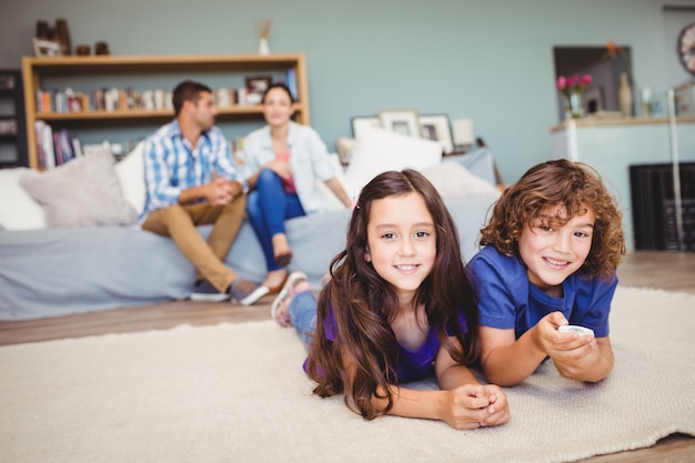 Happy children lying on carpet while parents