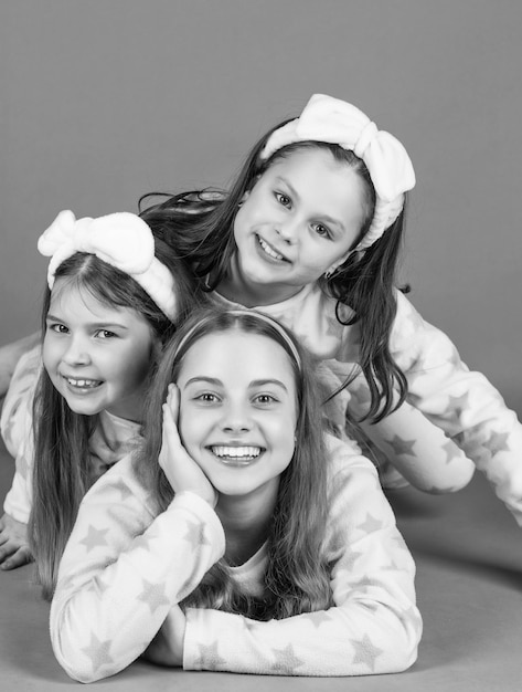 Happy children lying close on each other pink background Happy childhood portrait in pajamas