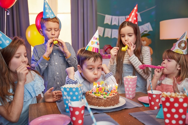 Happy children in party caps celebrating a birthday