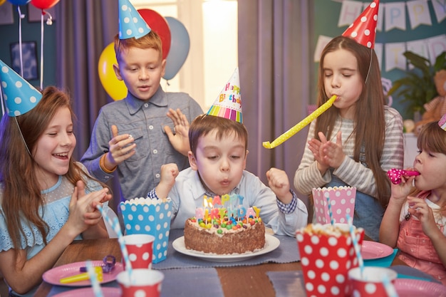Happy children in party caps celebrating a birthday