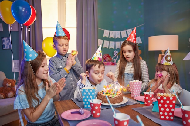 Happy children in party caps celebrating a birthday